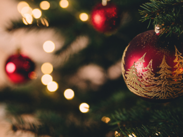 Close up photo of red and gold glitter Christmas ornament on a tree.