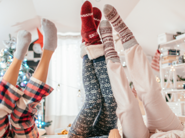 Photo of 3 people with their legs in the air wearing Christmas PJ's and socks
