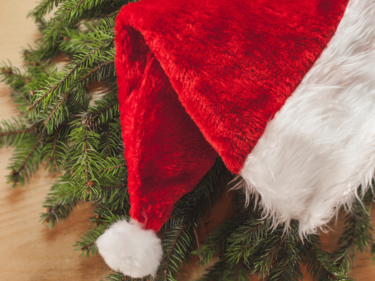 Photo of a Santa hat laid out onto some garland on a table.