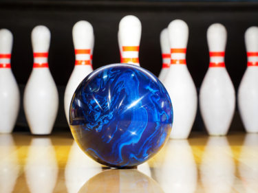 Image of a blue bowling ball in front of bowling pins set up in a lane.