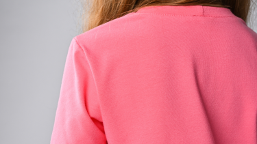 Photo of the back of a student wearing a pink shirt, only the shirt is shown.