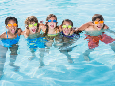 Group photo of 5 children swimming in a pool.