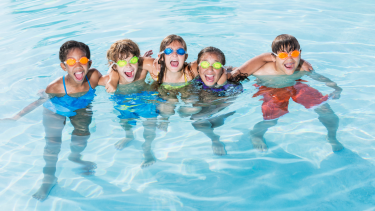 Group photo of 5 children swimming in a pool.