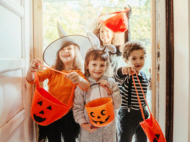 Children in Halloween costumes at the door entrance of an old house