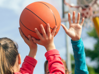 A close up photo of a child shooting a basketball.