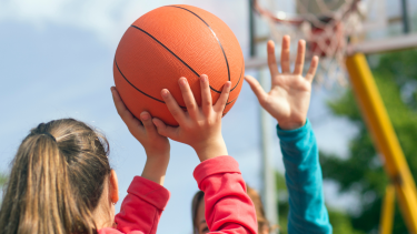 A close up photo of a child shooting a basketball.