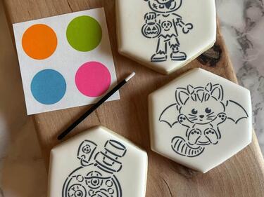 Photo of three paint your own cookies. A zombie, kitten-bat, and spooky potion.