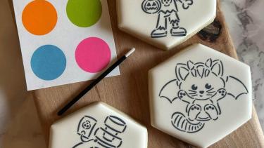 Photo of three paint your own cookies. A zombie, kitten-bat, and spooky potion.
