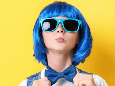 Photo of a child wearing a blue wig against a yellow backdrop