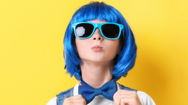 Photo of a child wearing a blue wig against a yellow backdrop