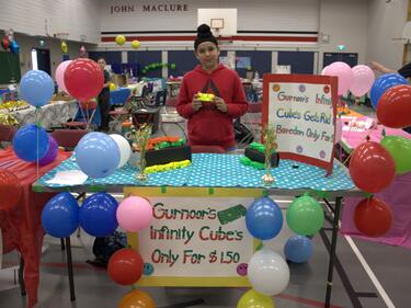 Photo of a student at his booth holding his product at our annual entrepreneur fair