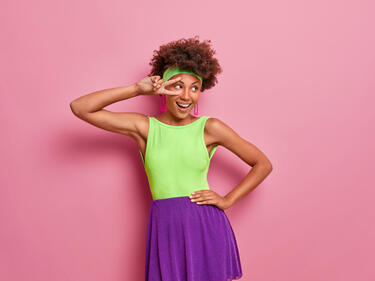 Photo of a women wearing brightly coloured clothing making a peace sign