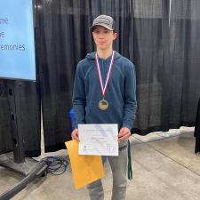 Male gold medalist stands with award