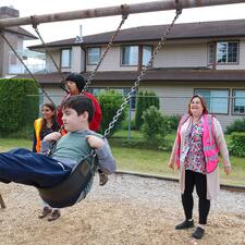 Female Educational Assistant pushed elementary school aged boy on swing