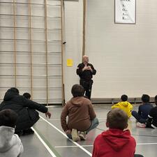 image of students sitting on the gym floor in front of Master Kinney.
